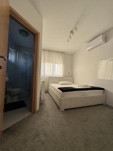 1 dormitorio con 1 cama y baño con lavamanos en Pansion Komfor Fitea, en Osijek