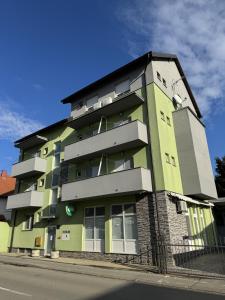 un edificio verde al lado de una calle en Pansion Komfor Fitea, en Osijek