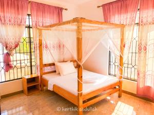 a bedroom with a canopy bed and windows at Raha house in Nungwi