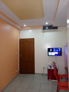 Habitación con puerta y TV en la pared en Appartement Aéroport 2, en Lomé