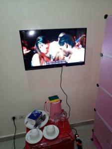 TV de pantalla plana colgada en una pared con mesa en Appartement Aéroport 2, en Lomé