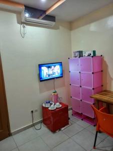sala de estar con TV y armario rosa en Appartement Aéroport 2, en Lomé