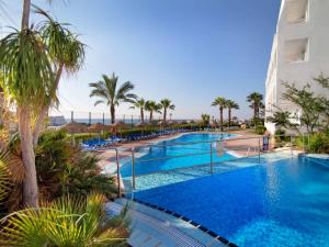 una piscina con palmeras y un edificio en Hotel Servigroup Marina Mar en Mojácar