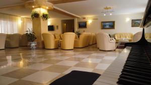 una sala de espera con piano y sillas amarillas en Hotel San Marco en Alghero