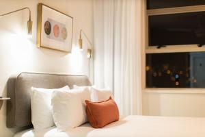 a bedroom with a bed with white pillows and a window at Habitat Aparthotel by Totalstay in Cape Town