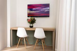 two white chairs sitting next to a table with a vase of flowers at Habitat Aparthotel by Totalstay in Cape Town