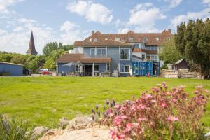 a house with a yard with flowers in the foreground at Hostel oder Ferienwohnung 1-16 Personen im BLAUEN HAUS in Fehmarn