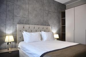 een slaapkamer met een groot wit bed met 2 lampen bij Hotel Building Stefan Resort I in Mamaia Nord – Năvodari