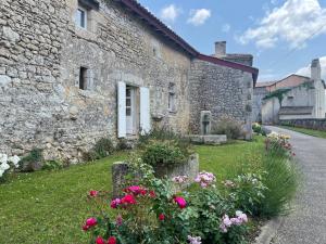 a stone house with flowers in front of it at Le Gîte du Prieuré in Bellefond