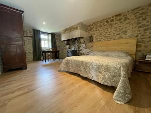 a bedroom with a bed and a stone wall at Le Gîte du Prieuré in Bellefond