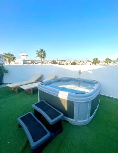 a hot tub sitting on the grass next to a beach at Nissi Avenue Suites in Ayia Napa