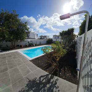 een zwembad in een tuin naast een hek bij VILLA ANNA With heated pool in Puerto del Carmen