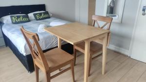 einen Holztisch und zwei Stühle neben einem Bett in der Unterkunft Studio on Golders Green Road in London
