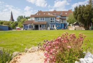 a house in a field with flowers in the foreground at Hostel oder Ferienwohnung 1-16 Personen im BLAUEN HAUS in Fehmarn