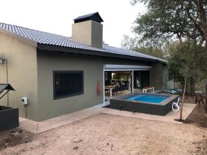 a house with a swimming pool in front of it at Modern Bush Living in Marloth Park