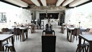 un restaurante con mesas y sillas de madera y una habitación con mesas en HOOGA Feel The Cosiness & Mysa Restaurant , Preveza en Preveza