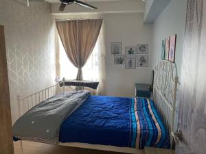 ein Schlafzimmer mit einem Bett mit einer blauen Decke und einem Fenster in der Unterkunft Condo in Klang. Nordica Gravit8 in Klang