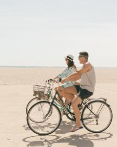 duas pessoas a andar de bicicleta na praia em Banana Beach Patacona Rooms em Valência