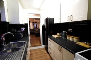 2BR Home W/ en-suite toilet, Town Centre Ipswich. في إبسويتش: مطبخ مع حوض وأعلى كونتر أسود