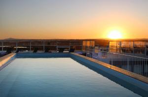 a swimming pool on the roof of a building with the sunset at AP Cabanas Beach & Nature - Adults Friendly in Cabanas de Tavira