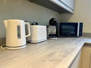 a kitchen counter with two toasters and a microwave at Pass the Keys Modern Family Friendly Flat with Parking in Rickmansworth