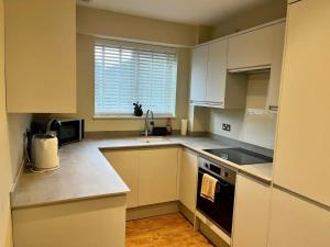 a kitchen with white cabinets and a sink and a stove at Pass the Keys Modern Family Friendly Flat with Parking in Rickmansworth