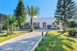 a house with palm trees and a driveway at Villa Ana to rent in Puerto Pollensa by JS Villas in El Port