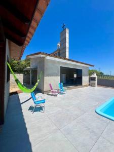 3 Stühle und eine Hängematte auf einer Terrasse neben einem Gebäude in der Unterkunft Casa Bella Italia con piscina in Içara