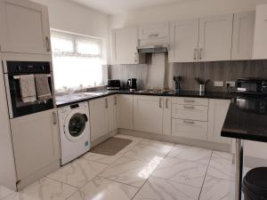 a kitchen with white cabinets and a washer and dryer at Bright Spacious Twin Room, next to Underground Station in Abbey Wood
