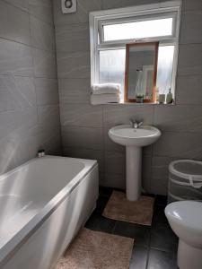 a bathroom with a tub and a sink and a toilet at Bright Spacious Twin Room, next to Underground Station in Abbey Wood