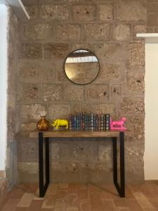 a table with books and a mirror on a brick wall at Civita Secret Lodge in Lubriano