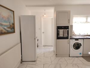 a white kitchen with a washer and dryer in it at Bright Spacious Twin Room, next to Underground Station in Abbey Wood