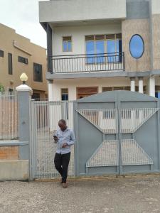 Ein Mann steht vor einem Zaun. in der Unterkunft Eric Hospitality Kigali BY KONGA in Kigali