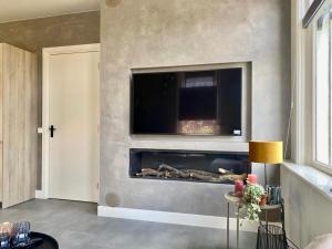 a living room with a fireplace with a tv above it at welkom bij 5 in Den Ilp