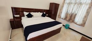 - une chambre avec un grand lit et une tête de lit en bois dans l'établissement HOTEL KANAK KUTEER, à Ayodhya