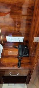 une table en bois avec un téléphone et une télécommande dans l'établissement HOTEL KANAK KUTEER, à Ayodhya