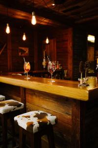 a bar with two wine glasses and two stools at Alpine Hotel Perren in Zermatt