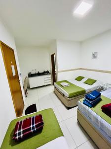 two beds in a white room with green sheets at Flat Gru in Guarulhos