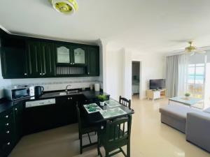 eine Küche und ein Wohnzimmer mit grünen Schränken und einem Tisch in der Unterkunft Sand and Sea in Puerto de Santiago + 3 Fotos