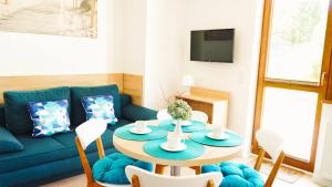 a living room with a table and a blue couch at Promyki - Domy Apartamentowe in Chłopy