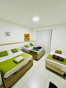 - 3 lits dans une chambre avec des tons verts et blancs dans l'établissement Flat Gru, à Guarulhos