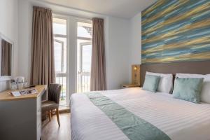 um quarto de hotel com uma cama, uma secretária e uma janela em The County Hotel em Llandudno