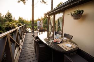 eine Holzterrasse mit einem Tisch und Stühlen auf dem Balkon in der Unterkunft Silene Resort & Spa in Silene