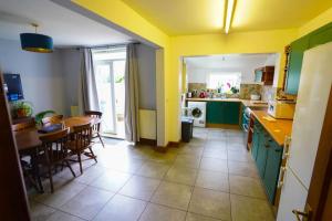 uma cozinha com armários verdes e uma mesa e cadeiras em 3 Bedroom Home in the Dale’s, Very close to Ipswich town centre. em Whitton