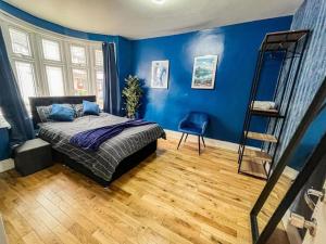 1 dormitorio con paredes azules, 1 cama y una escalera en East London Townhouse by Harlington, en Londres