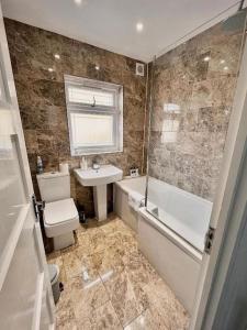 a bathroom with a toilet and a sink and a bath tub at East London Townhouse by Harlington in London