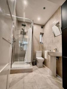 a bathroom with a shower and a toilet and a sink at East London Townhouse by Harlington in London