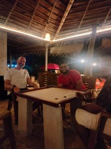 two men sitting at a table in a restaurant at Revibe Beach Hostel Gokarna in Gokarna