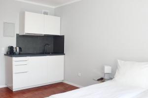 a white kitchen with a sink and a bed at Hometown-Apartments in Heidelberg