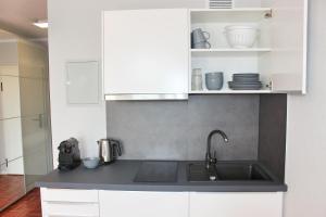 eine Küche mit einem Waschbecken und weißen Schränken in der Unterkunft Hometown-Apartments in Heidelberg